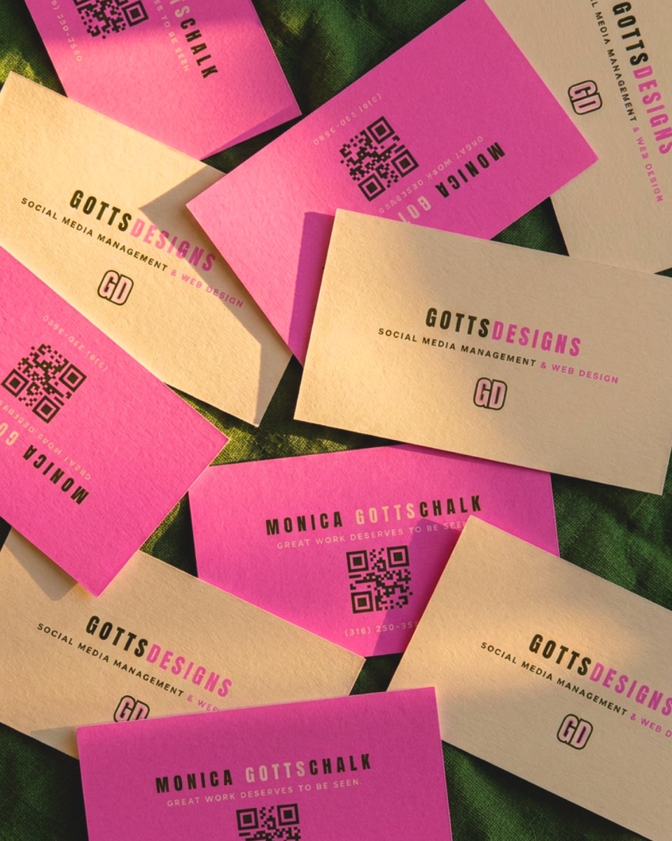 GottsDesigns business cards in pink and cream, styled on green fabric